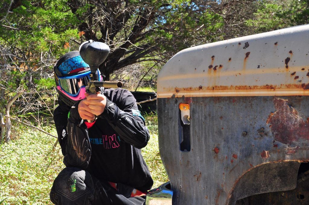 Paintball players moving between field obstacles
